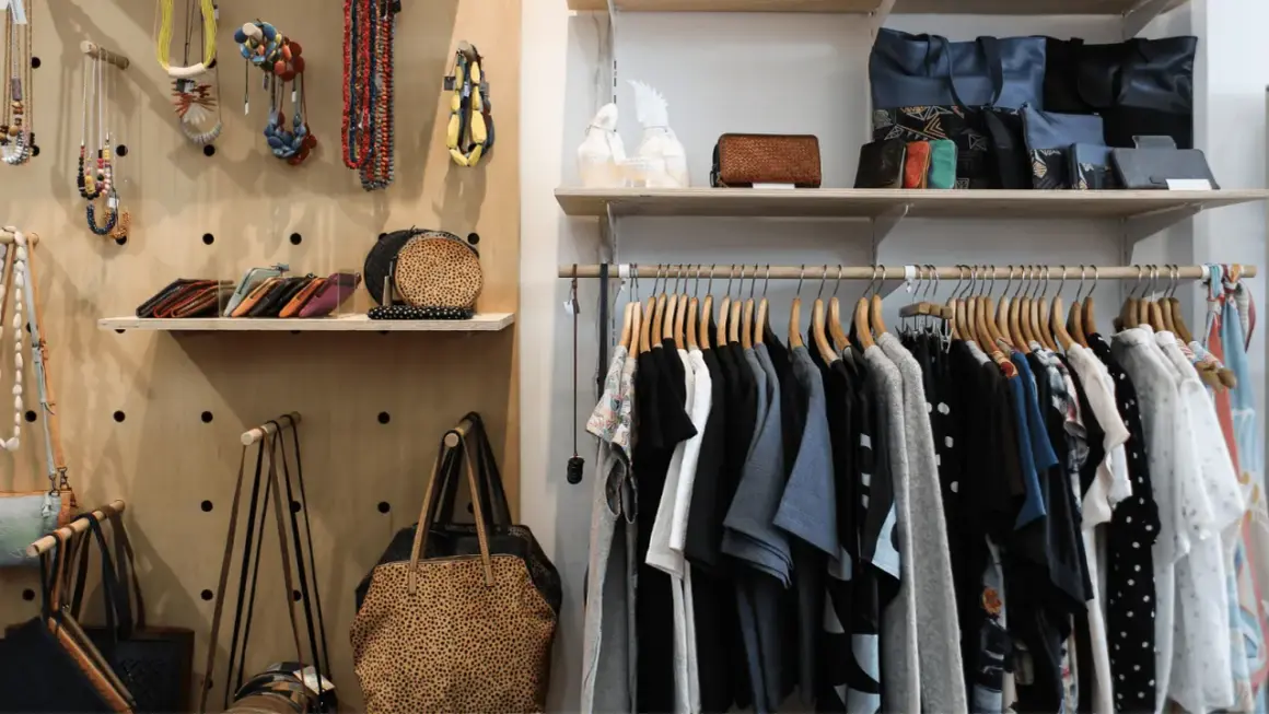 Hängande kläder och accessoarer i en butik. En hel del kläder, väskor och smycken som kan utgöra en komplett outfit.
