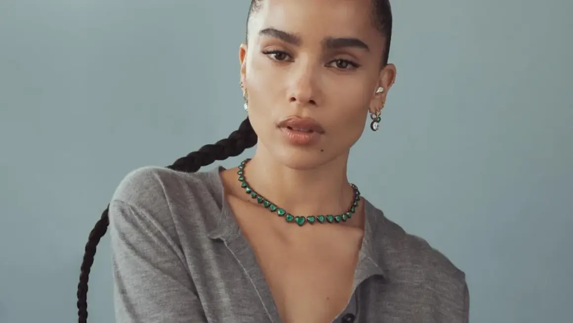Zoe Kravitz stil: en kvinna med flätat hår bär en grön hjärtformad halsband och örhängen.