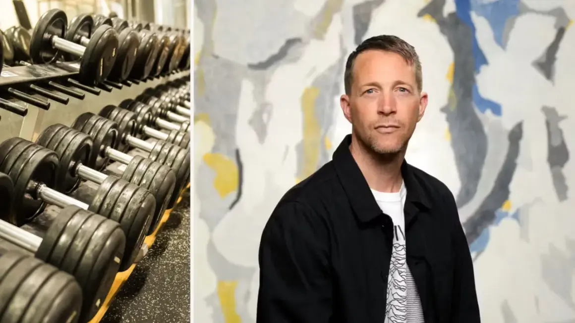 En man med en blick som antyder "looksmaxxing meaning" står framför en abstrakt tavla. Till vänster syns en hylla med hantlar.
