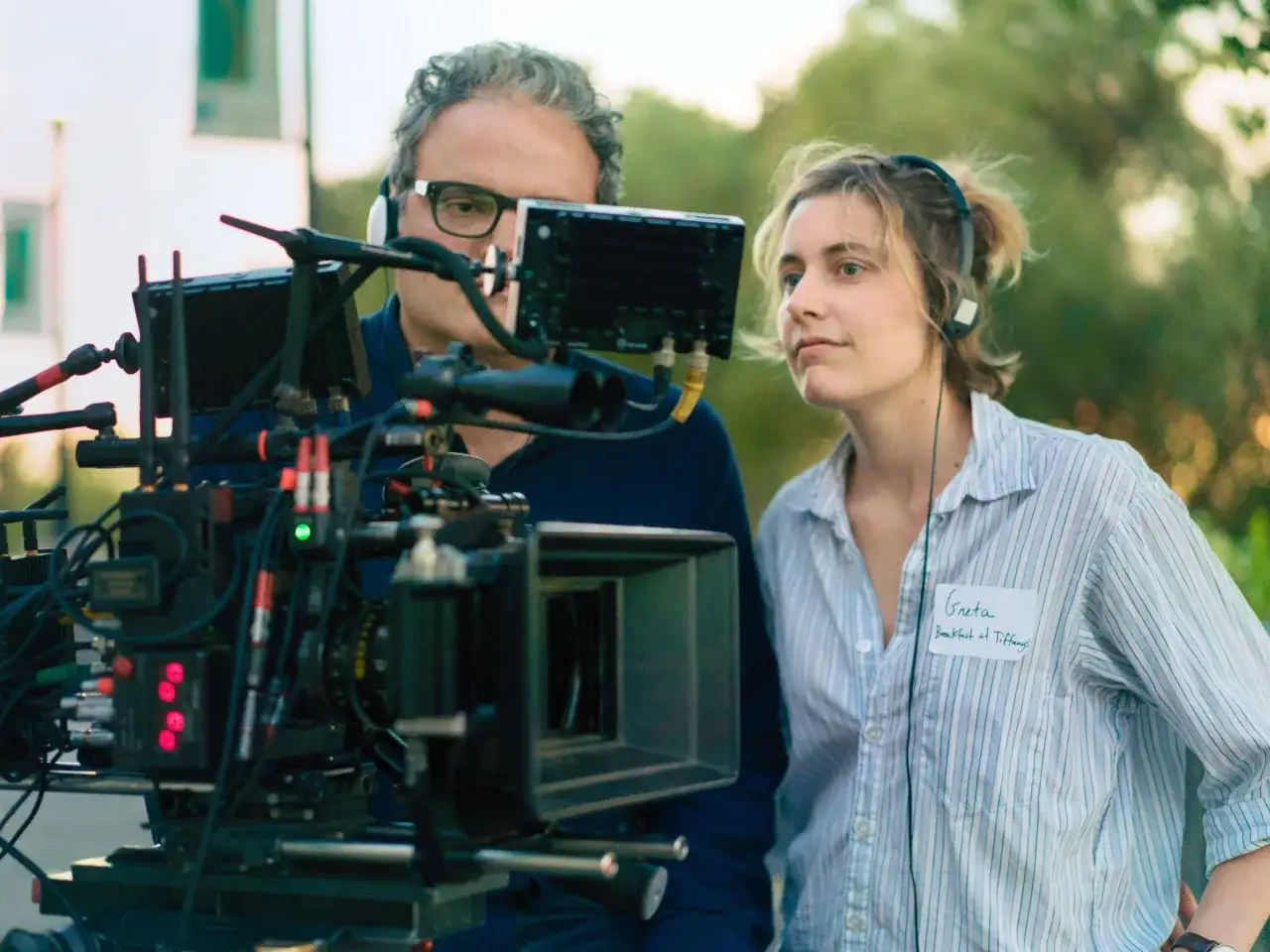 Greta Gerwig, med hörlurar och en namnskylt för