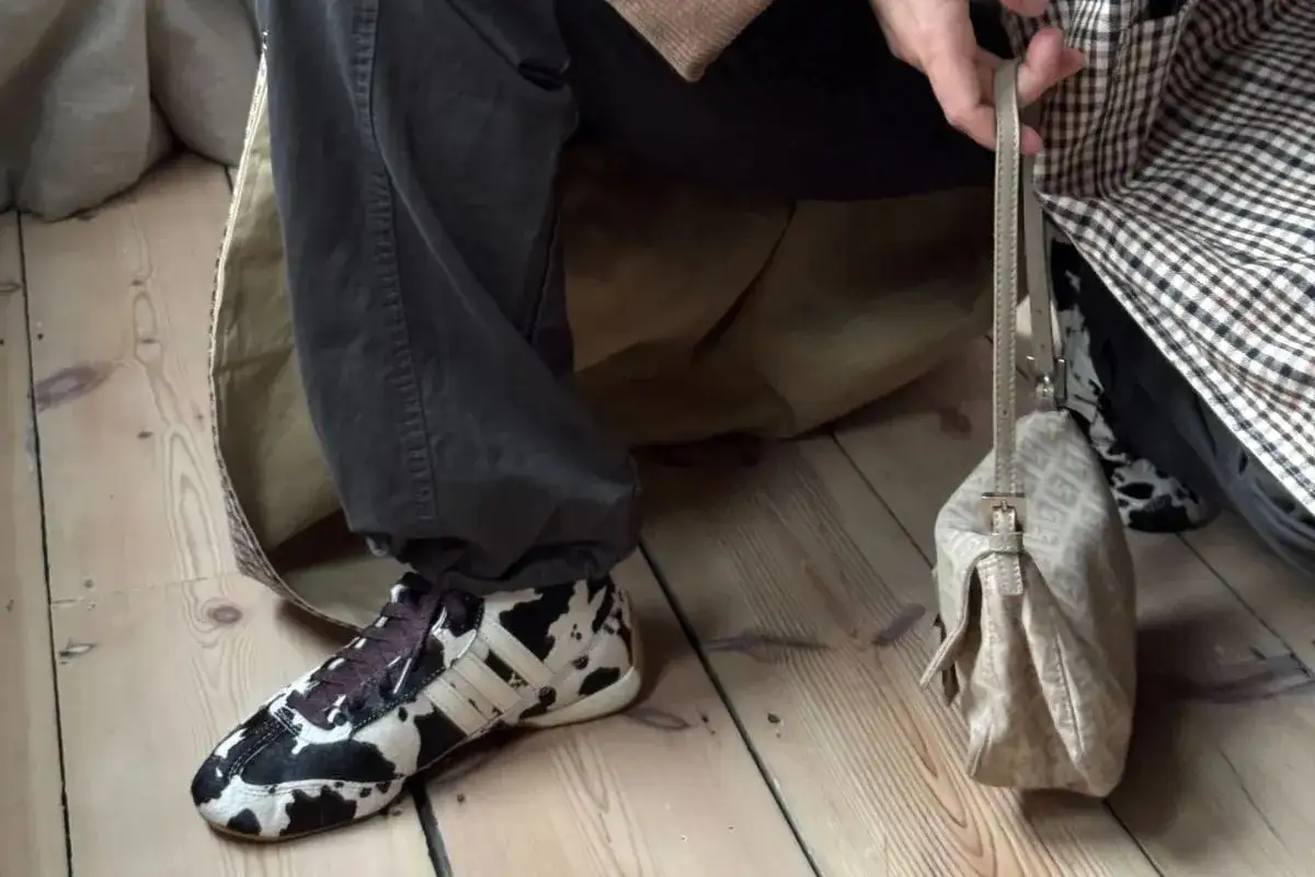 Person med cowprint-mönstrade, lite fula skor och en beige handväska.