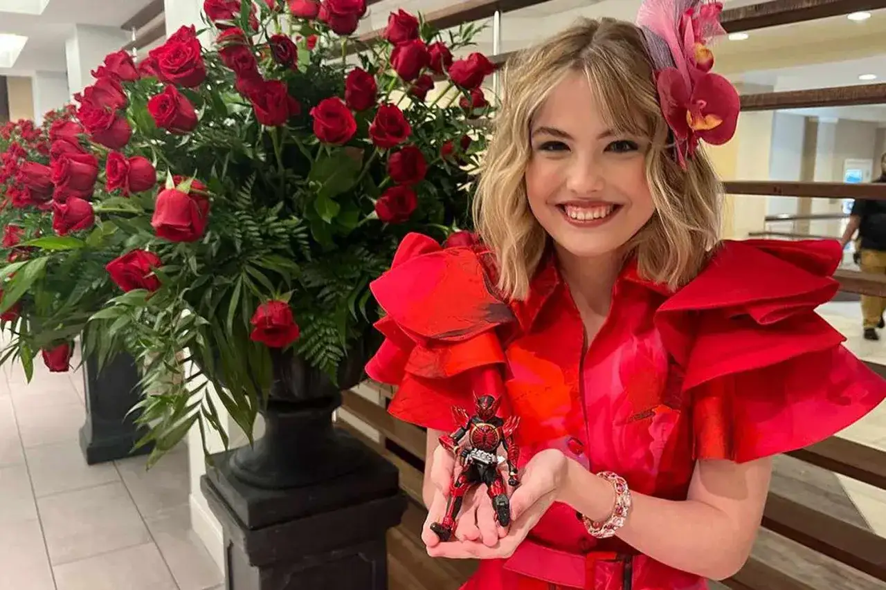 Glad leende flicka med en actionfigur, omgiven av röda rosor. Kanske anna nicole smith dotter?