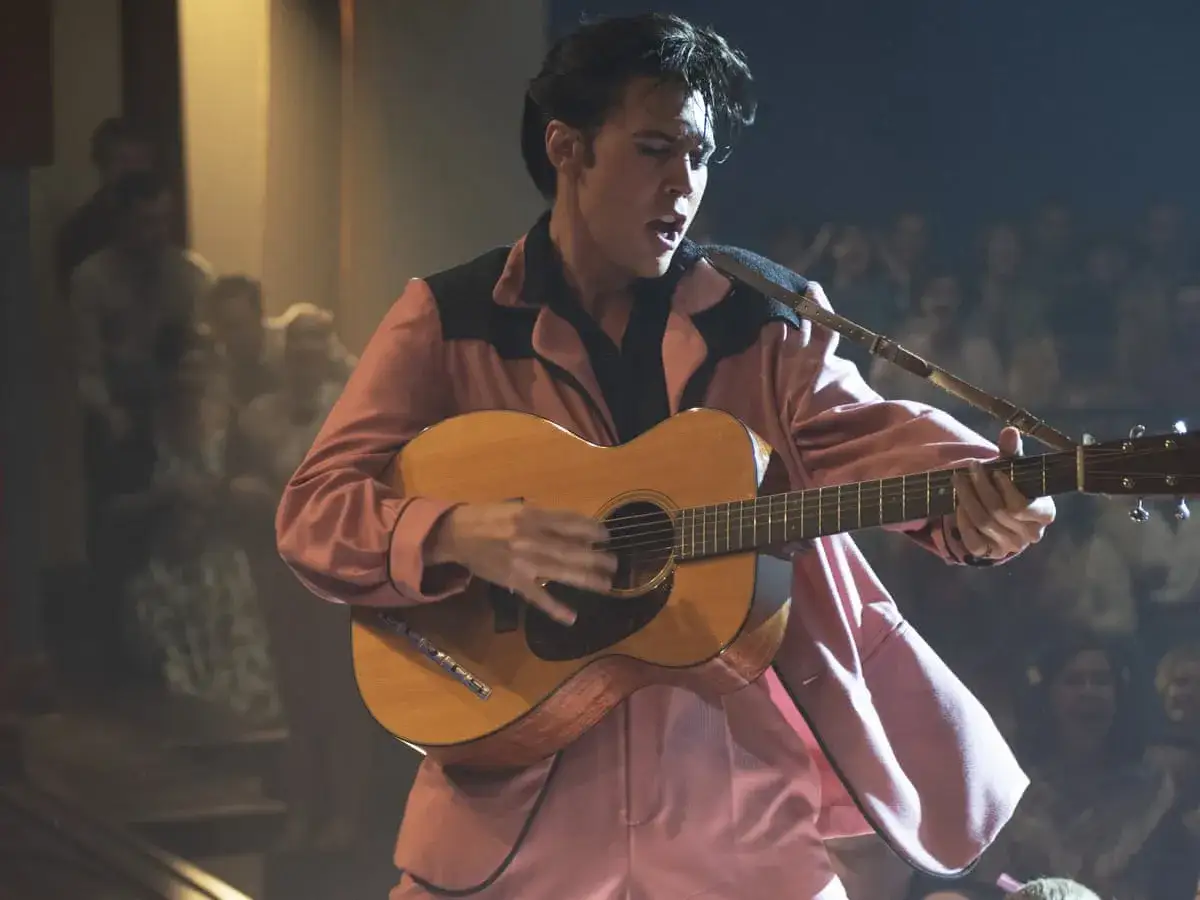 Austin Butler som Elvis Presley i en av Baz Luhrmans filmer, spelar gitarr på scenen inför en jublande publik.