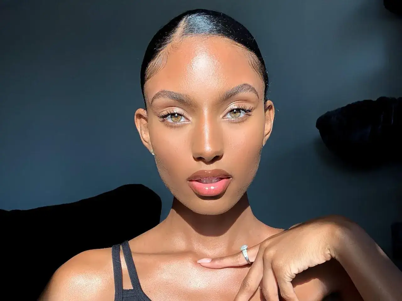 En ung kvinna med en naturlig, ren look. Hennes hud är glödande och hennes läppar är glansiga, en perfekt clean girl makeup.