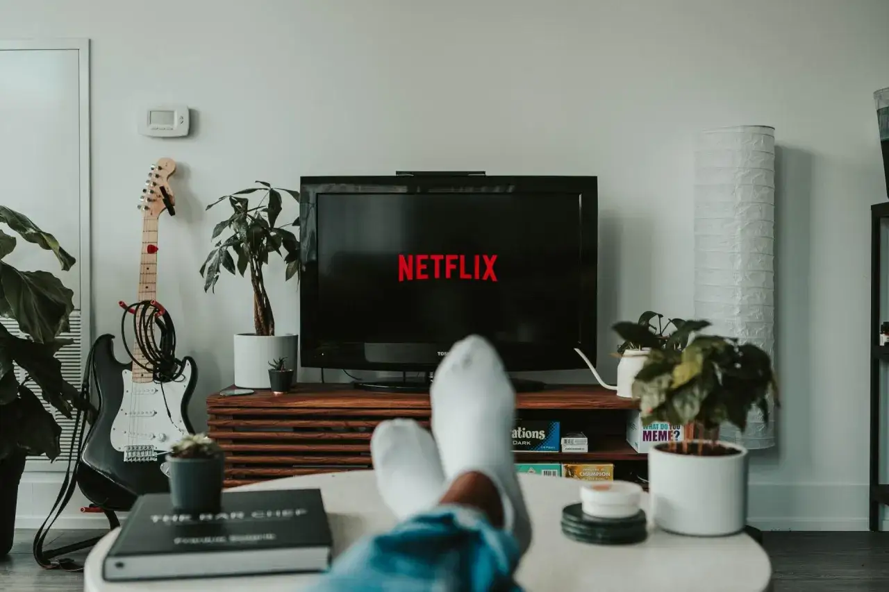 Fötter i strumpor vilar medan Netflix laddas. En elgitarr står redo för en paus från binge watching.