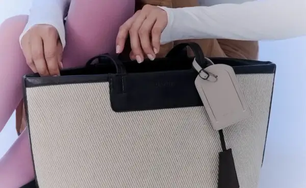 En person med rosa strumpbyxor och vit tröja stoppar ner handen i en necessär från Day Birger et Mikkelsen.