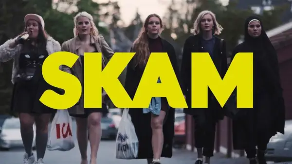 Fem tjejer går på gatan, med den stora gula texten "SKAM" över bilden. En av dem dricker ur en flaska.