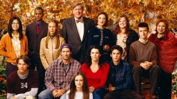 Hela rollistan i Gilmore Girls samlad framför höstfärgat lövverk. En ikonisk ensemblebild som fångar seriens charm.