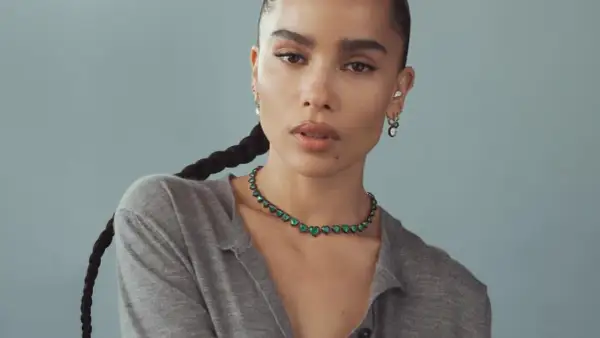 Zoe Kravitz stil: en kvinna med flätat hår bär en grön hjärtformad halsband och örhängen.