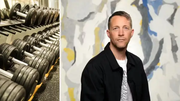 En man med en blick som antyder "looksmaxxing meaning" står framför en abstrakt tavla. Till vänster syns en hylla med hantlar.